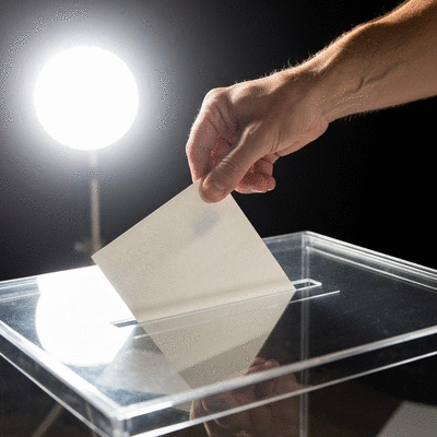 Conceptual image of a voter's hand placing a ballot into a clear box, representing transparency and participation in primary elections, clean image, no text, no words